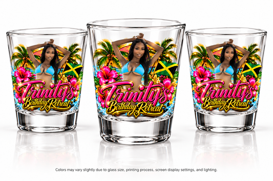 Three clear personalized shot glasses featuring a vibrant tropical Jamaica birthday retreat design with pink hibiscus flowers, palm trees, a Jamaican flag, a woman in blue, and pink-and-gold Trinity's Birthday Retreat lettering. Displayed on a white studio background.